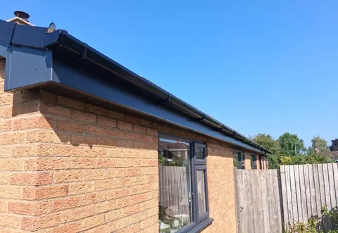 Anthracite grey fascia, soffit and guttering along the eaves of a brick bungalow, above a matching grey window